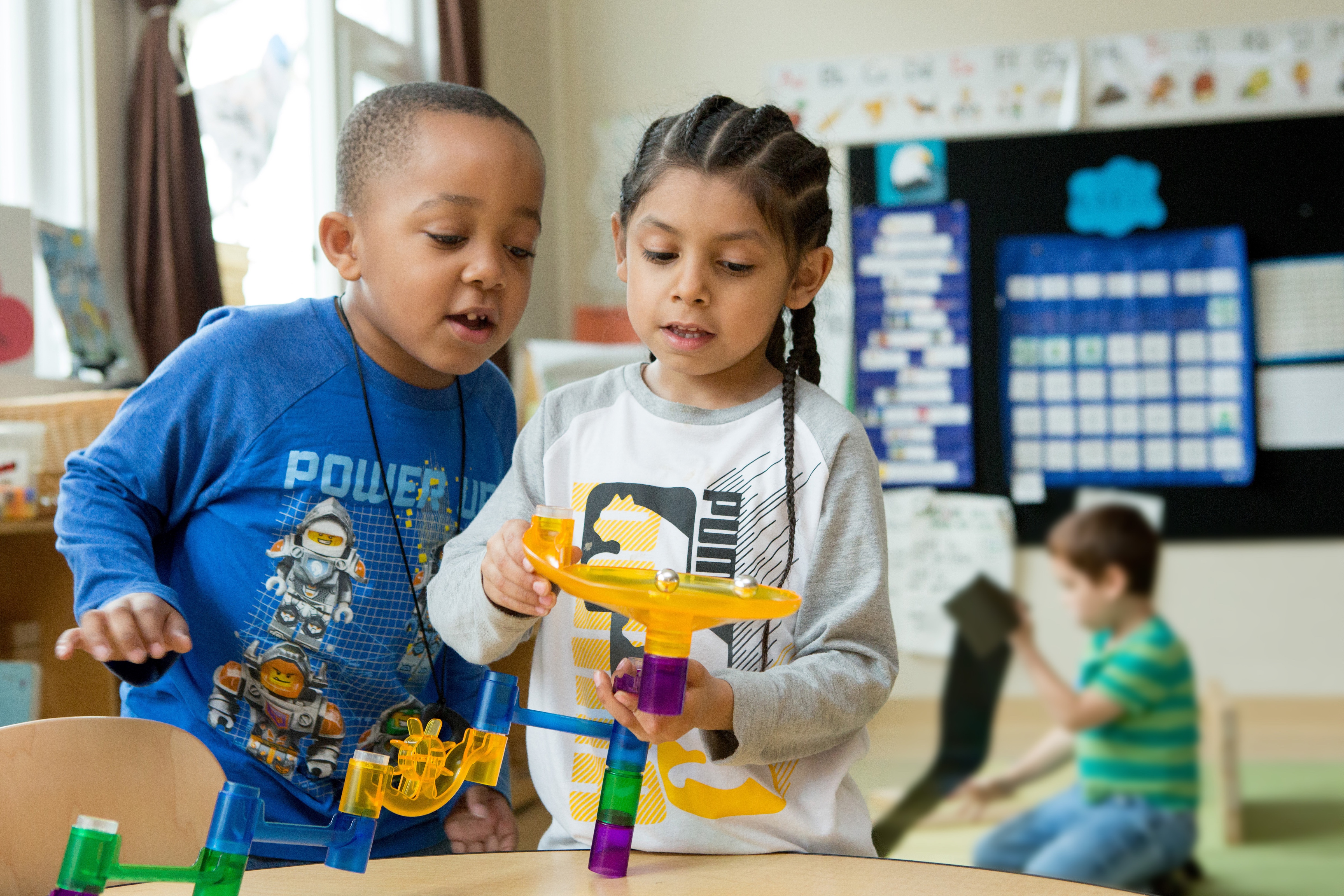 Two kindergarteners play with marbles