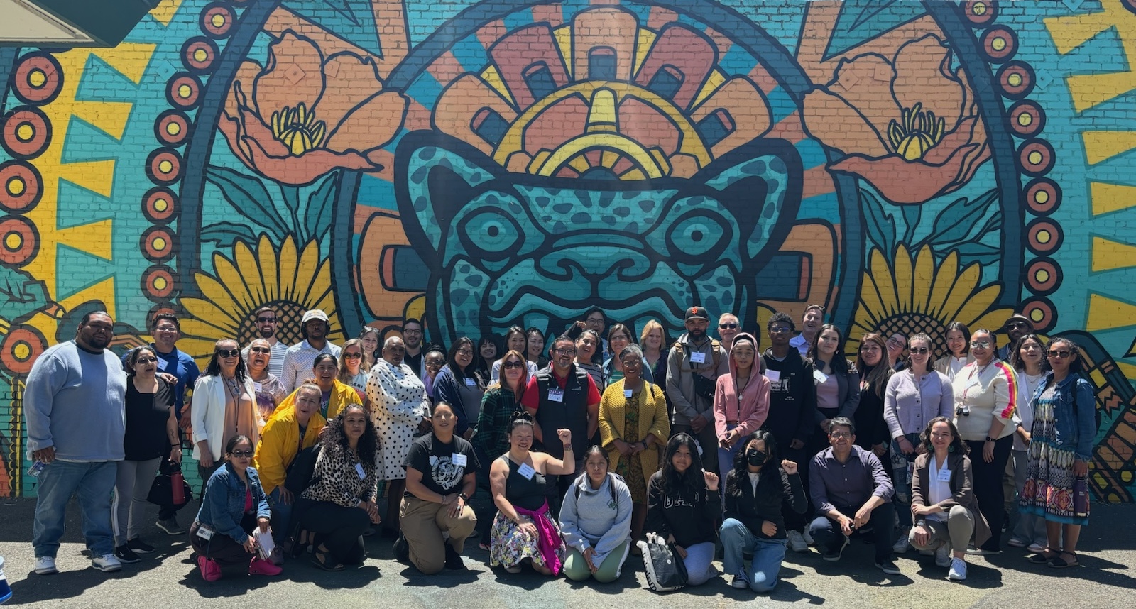 diverse group of school and community leaders in front of a colorful mural