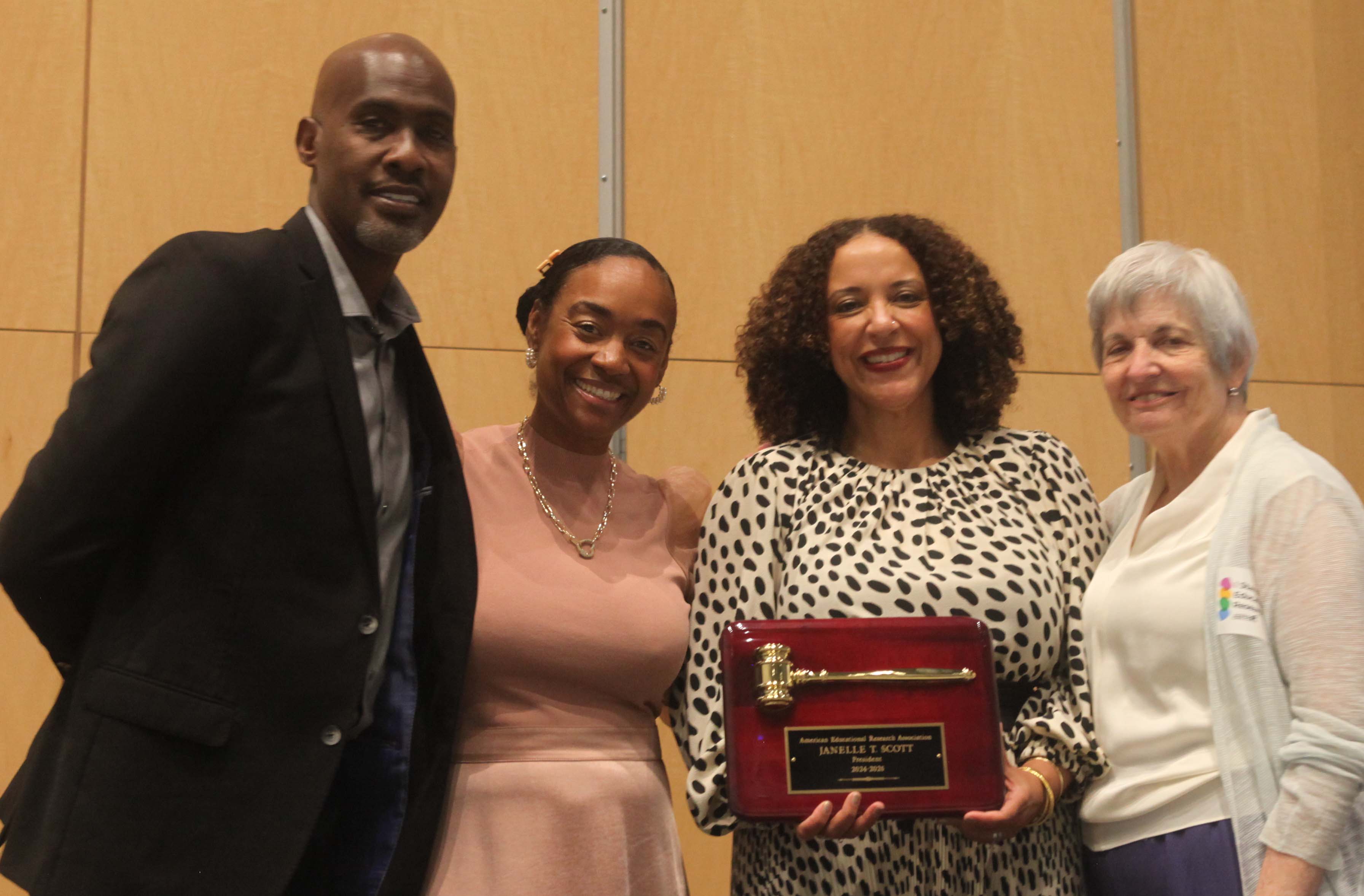 four people standing next to each other are Tyrone C Howard, Maisha T Winn, Janelle Scott who is holding a plaque with a gavel, and Felice J Levine