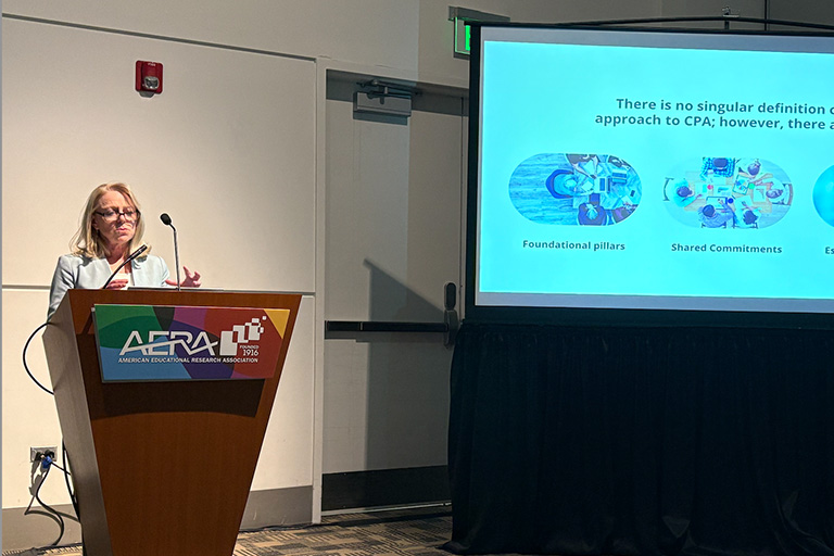 michelle young at podium presenting her paper and on the left is a slide from her presentation