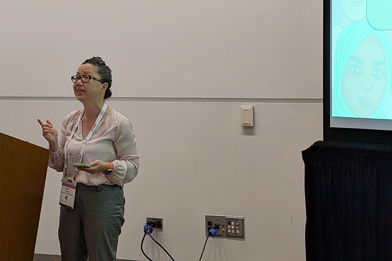 mai xi lee standing next to podium presenting her research