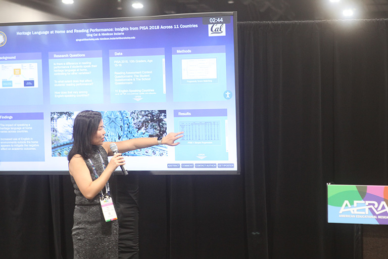 qing cai looking and pointing at her poster 