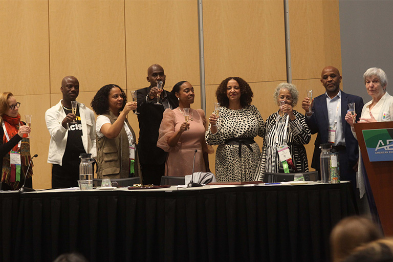 Nine people on stage with champagne glasses giving a celebratory closing toast