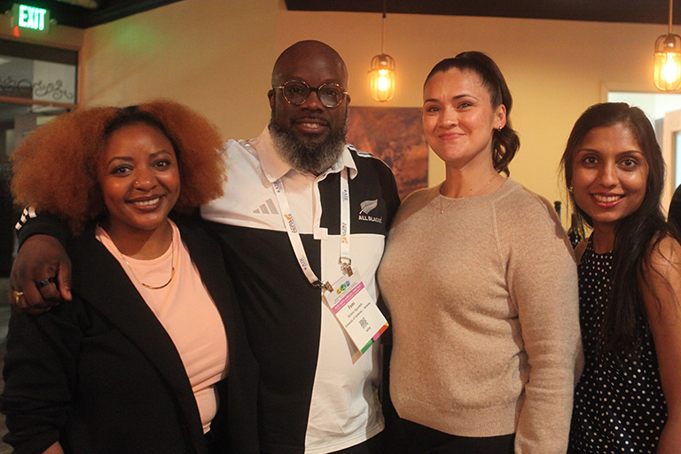 four people standing next to each other smiling at camera