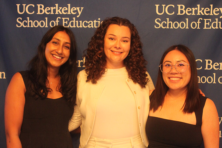 three people standing in front of the u c bekeley school of education back drop all smiling at the camera