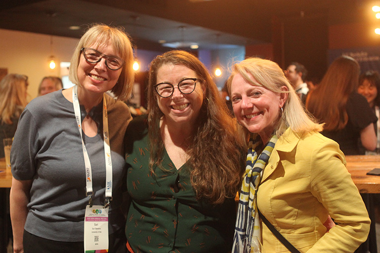 three people standing in a line next to each other smiling at camera