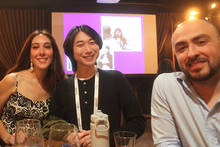 three people standing around a high table all smiling at camera