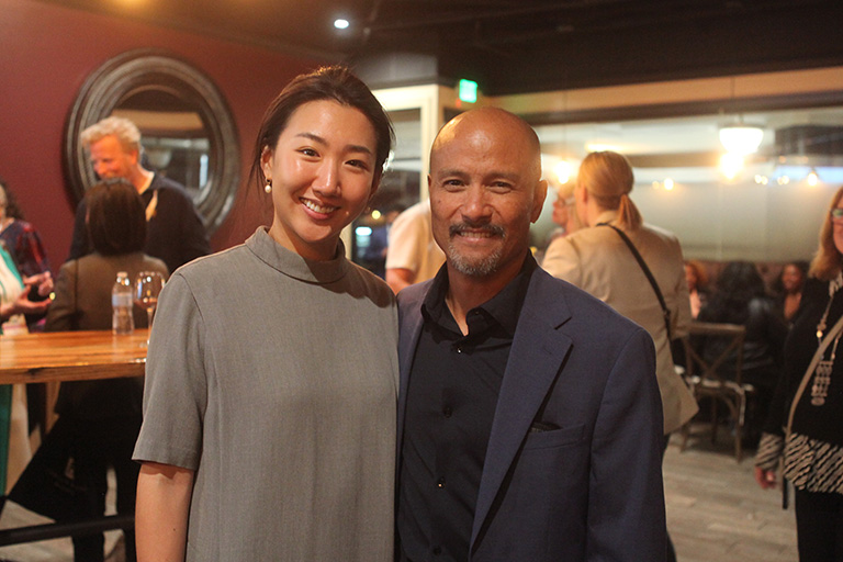 two people standing next to each other at the reception smiling at camera