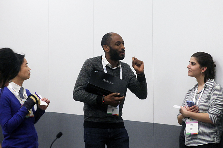 doctoral student aukeem ballard standing with a group and taking with others about research findings