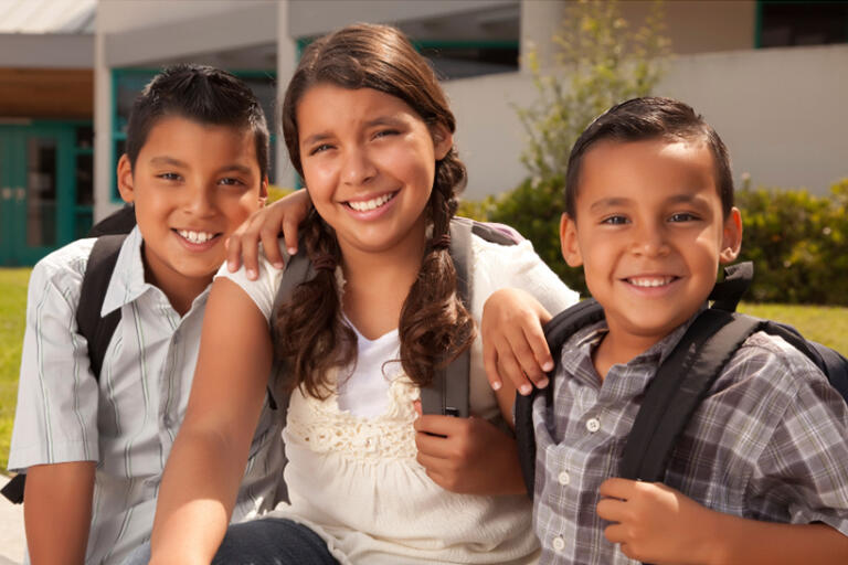 three young siblings smiling at camera