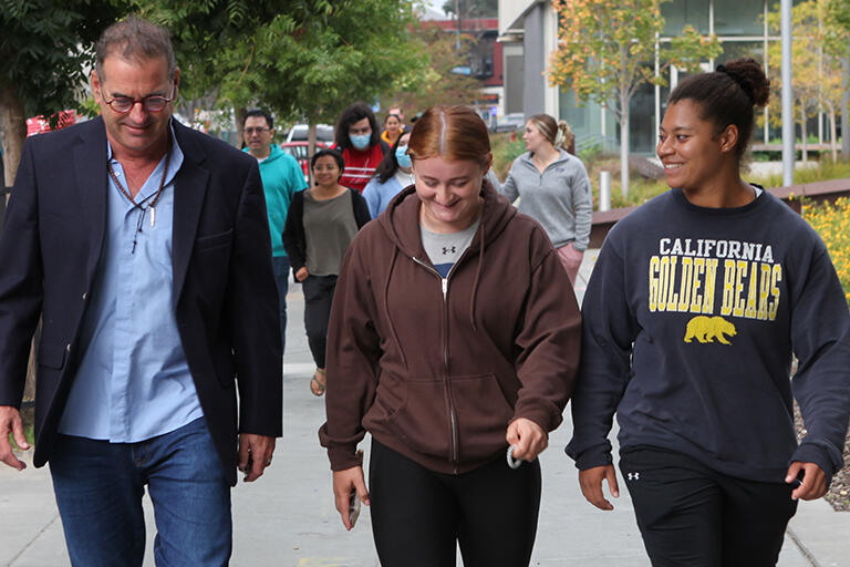 adjunct professor derek van rheenen on the left walking with two students