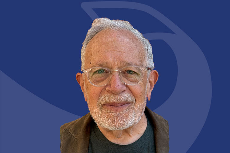 robert reich smiling at camera blue background with faded ribbon