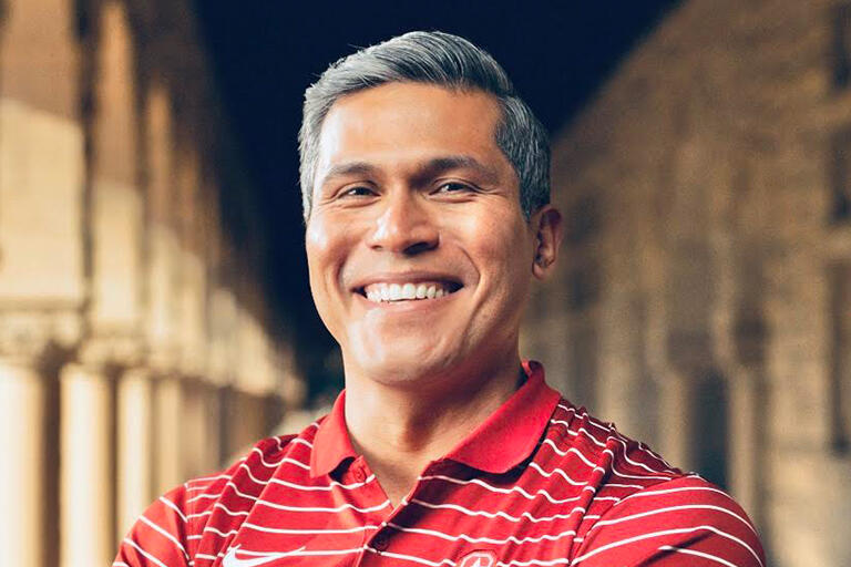 doctoral student samuel santos smiling at camera wearing red shirt with thin white stripes