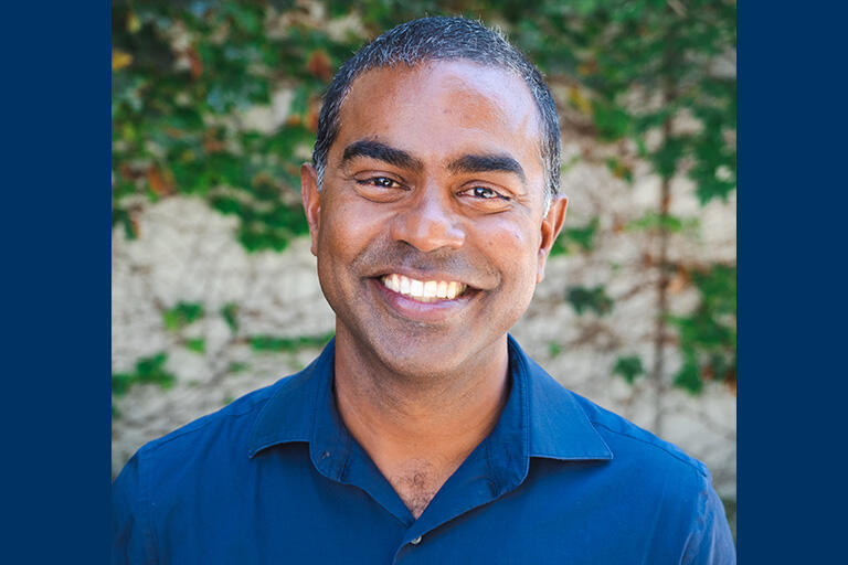professor thomas philip smiling at camera wearing blue button up shirt