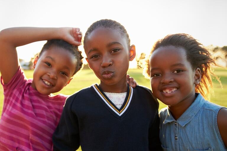 three Black children pose outdoors