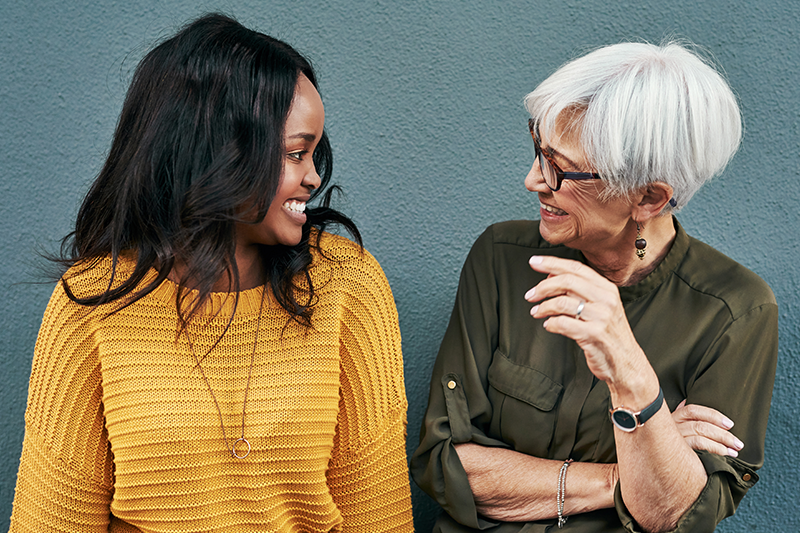 Younger woman of color talking and laughing with an elder mentor