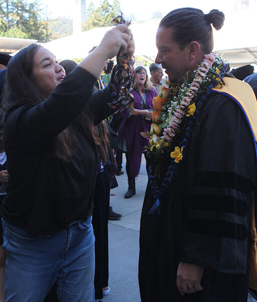 a family member giving a graduate several leis made from hawaiian tea leaves