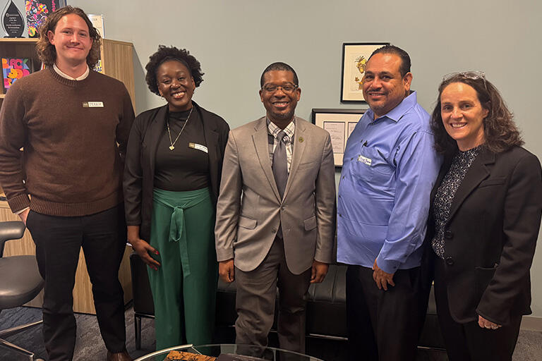 five people standing next to each other all smiling at the camera