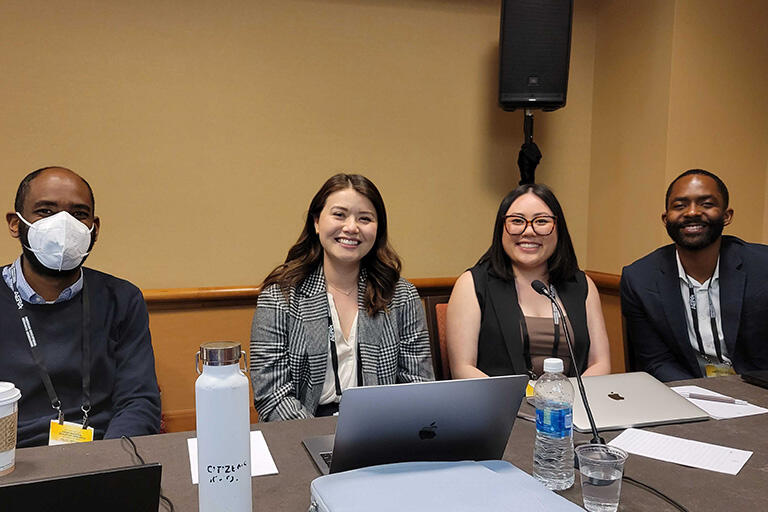 four people from 21csla sitting at table smiling at camera