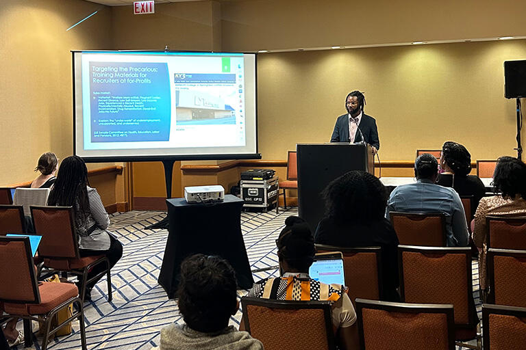 doctoral student caleb dawson at podium speaking to seated attendees