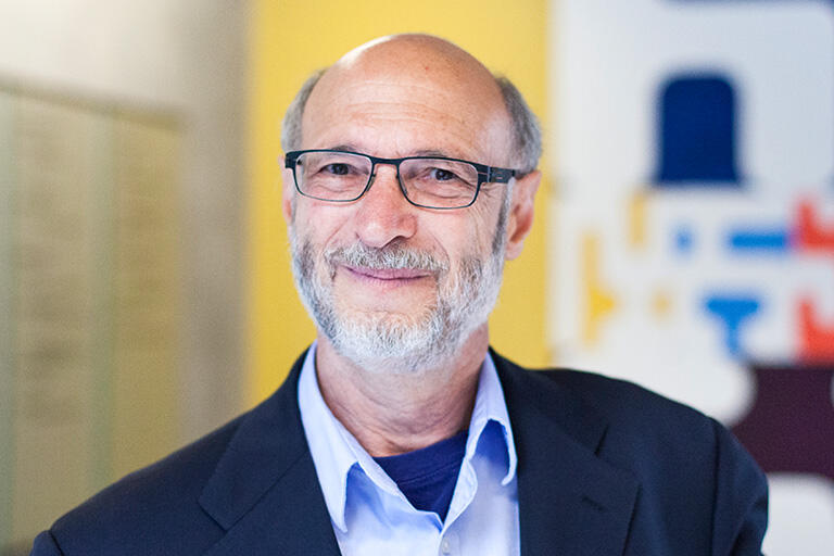 Professor Alan Schoenfeld smiling at camera wearing light colored button up shirt and blue sports coat