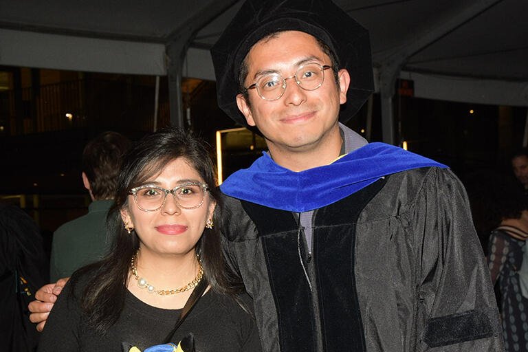 doctoral graduate standing with family member both smiling at camera