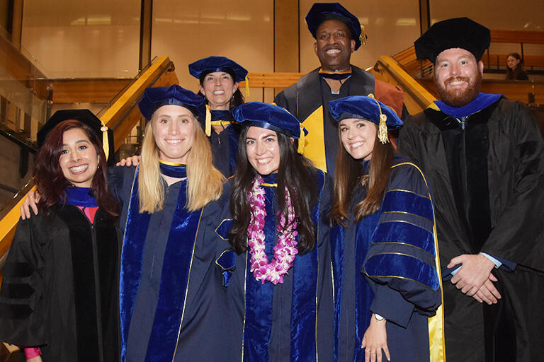 five school psychology program graduates smiling at camera with program director kate perry and faculty director frank worrell behind them