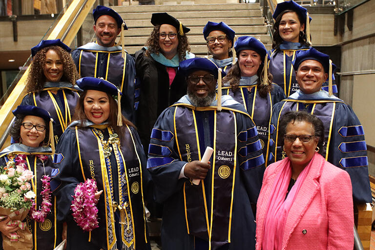 group image of E D D graduates with U C Berkeley Foundation Trustee Lisa Jones in front wearing pink jacket and scarf