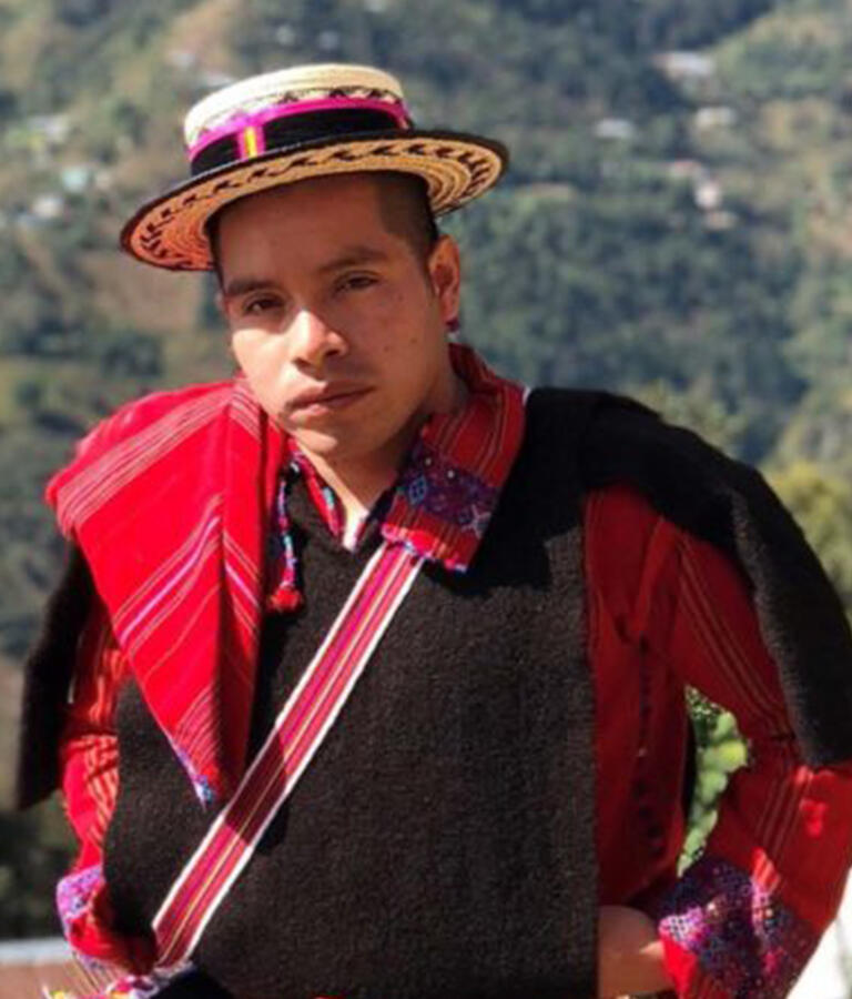 doctoral student henry sales looking at camera wearing clothing of his Guatemalan Mayan culture