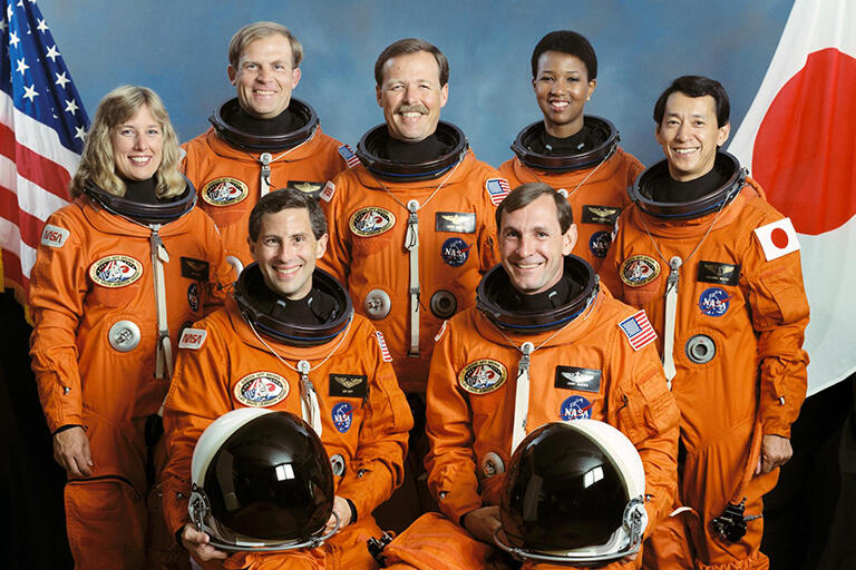 doctor mae jemison and six shuttle crewmates pose for group photo wearing orange nasa space suits