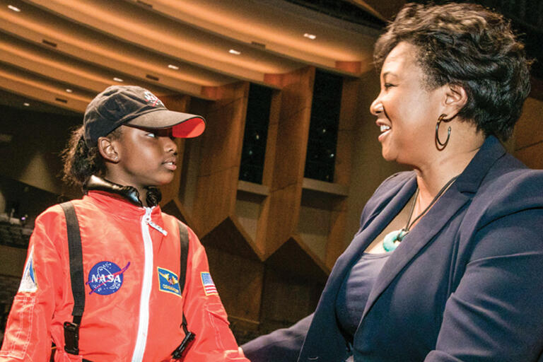 doctor mae jemison talking with a young student who is dressed in an orange nasa space suit