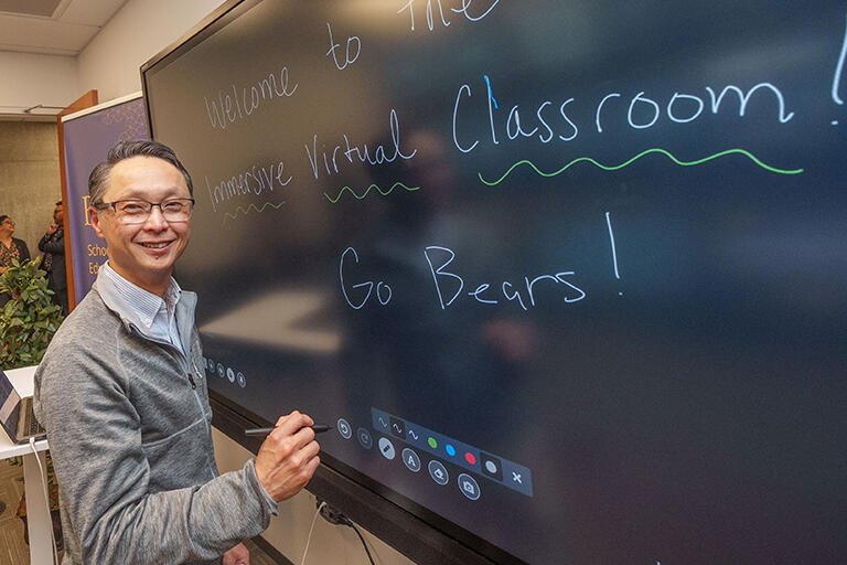a person has written on the instructor's electronic board and is smiling at the camera