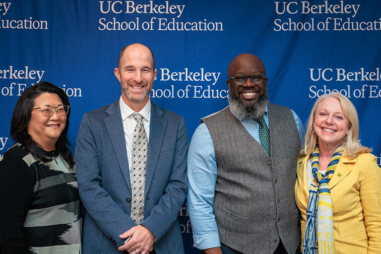 from left to right, rebecca cheung, joshua daniels, femi ogundele, and michelle young standing in front of a back drop with the u c berkeley school of education logo and all smiling at camera