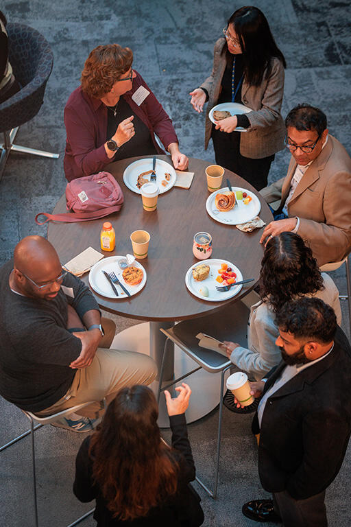 view from above of people around a table socializing four people are sitting and three people are standing