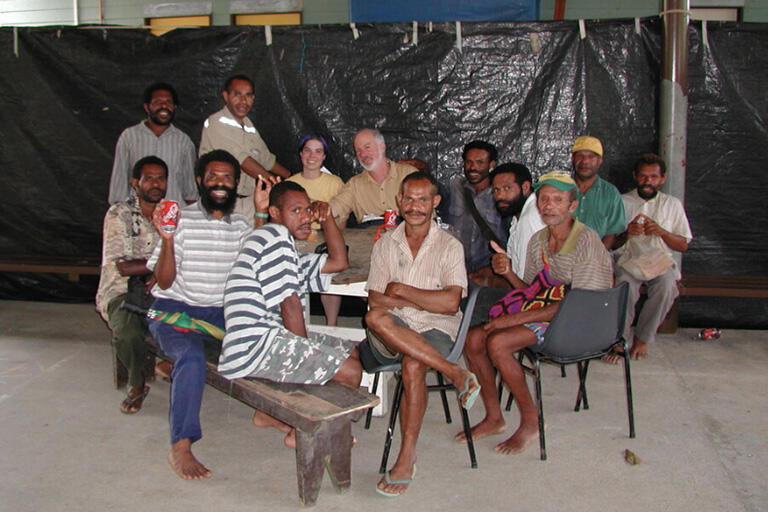 professor saxe sitting a table with local friends in Tabubil in 2001 everyone is looking at camera