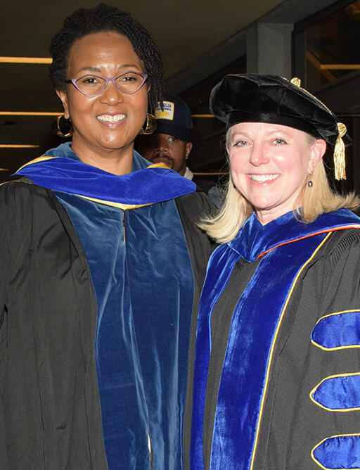 doctor mae jemising and dean michelle young standing next to each other both wearing regalia and smiling at camera