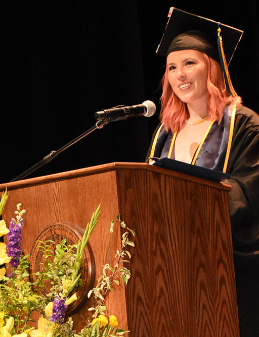 master's degree student aimee eagle at podium giving her speech