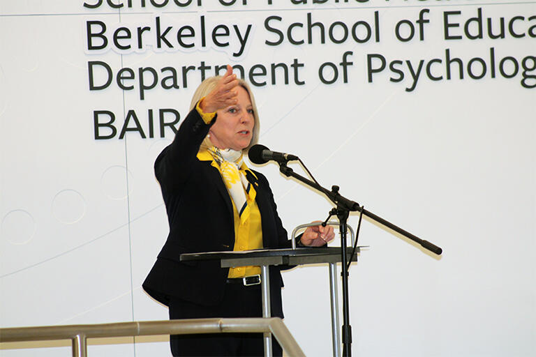 dean michelle d young at the podium talking and gesturing with right hand