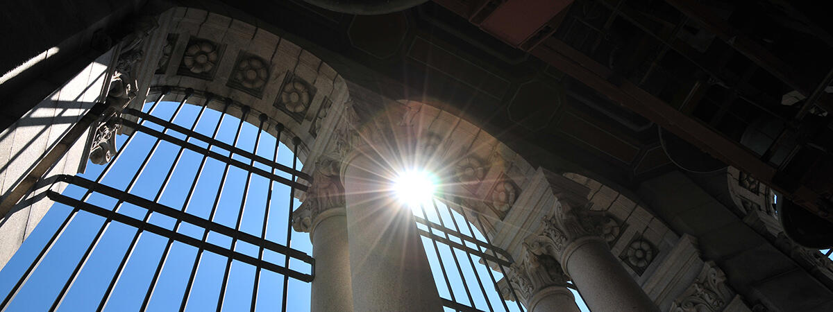 looking out from the top of the campanile toward the sky with a sun spot shining through