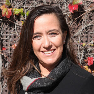 adjunct professor Ozge Hacıfazlıoğlu smiling at camera long brown hair black scarf and sweater